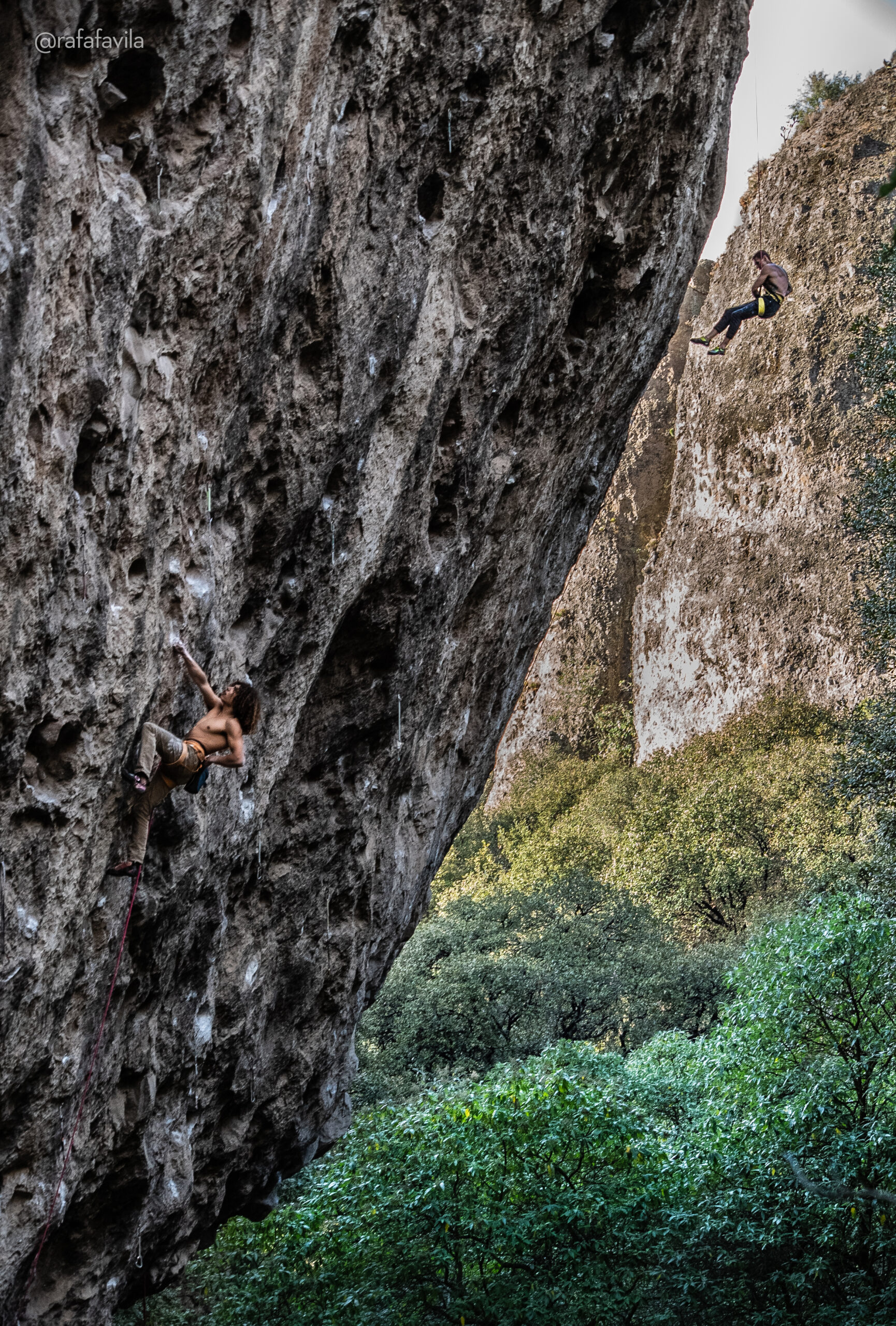 Two rock climbers in a cliff, trying to send some hard routes, the rock is an overhanging wall.